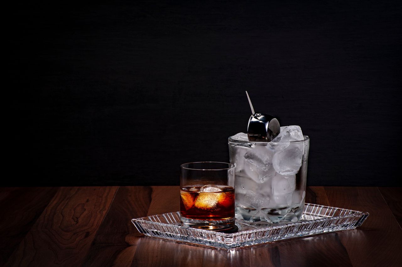 Close-up of a whiskey glass with ice cubes on a wooden table, perfect for drinks advertising.